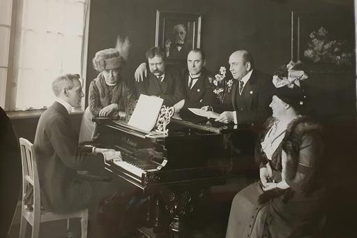 Wilhelm Stenhammar sittande vid flygel tillsammans med musiker och dirigenter